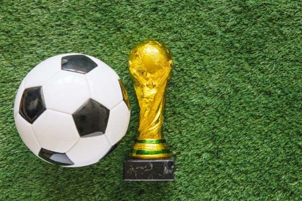 "FIFA World Cup 2026 trophy and football on grass."